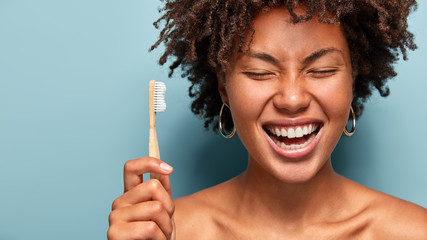 Dental health concept. Happy smiling dark skinned woman with curly hair, laughs while has morning...