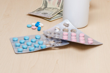 Blue and pink pills and dollars on the table