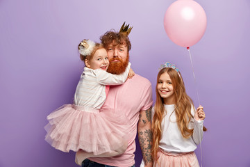International Family Day. Sad redhaired bearded dad holds daughter on hands, tired after noisy...