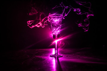 Closeup wine glass with fog at dark background. Beautiful glass with smoke and light.