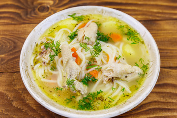 Chicken soup with noodles and vegetables on wooden table