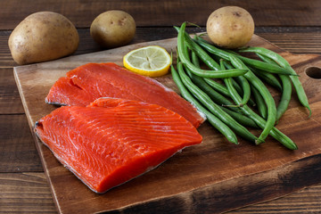 Sock eyed salmon with organic green beans, potatoes and lemon on wooden cutting board