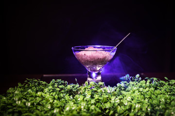 Glass filled with colorful fruit ice cream on dark background with toned light and fog