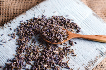 Close-up of dry lavender in spoon on a wooden kitchen board. Aromatherapy or cooking process