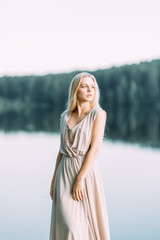 Fototapeta na wymiar Girl in boudoir dress by the lake at sunset. Fees bride's on nature, harmony. Beautiful model, Russian girl with long hair
