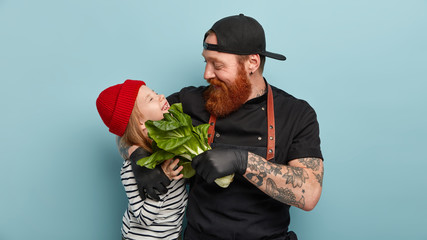 Affectionate father returns from grocers shop, plays with daughter, touches face with bokchoy,...