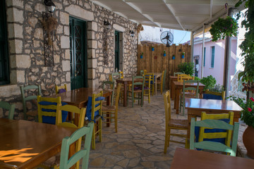 Traditional old Greek cafe tavern with blue doors and chairs on sidewalk,Lefkada, Greece