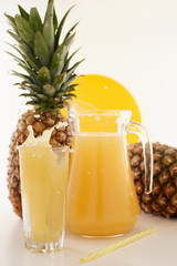 Jug and glass of pineapple juice with fruits on white background. Splash yellow drink. 