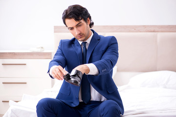 Young handsome businessman choosing shoes at home 