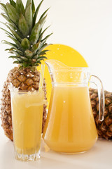Jug and glass of pineapple juice with fruits on white background. Splash yellow drink. 
