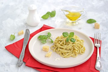 Spaghetti with pesto sauce and parmesan cheese on a white ceramic plate. Italian food.