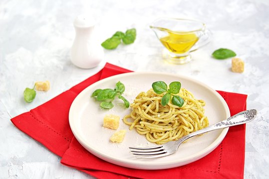 Spaghetti with pesto sauce and parmesan cheese on a white ceramic plate. Italian food.