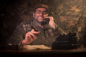 The evil dictator sitting on table. Angry communist general sitting at headquarter or Cuban...