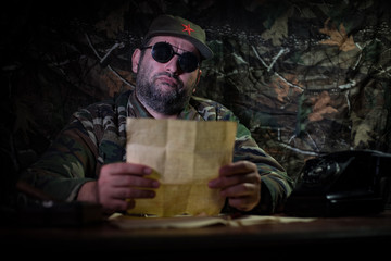 The evil dictator sitting on table. Angry communist general sitting at headquarter or Cuban...
