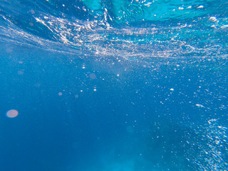 Air bubbles under the water rise up. Beautiful texture of sea and ocean water. Aerial blue background. Underwater photography.
