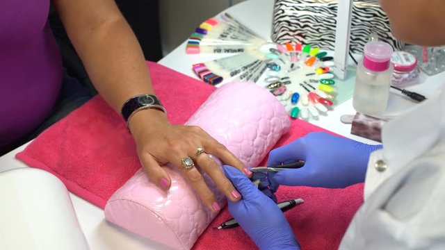 Manicurist clipping hangnail with cuticle nippers in a beauty salon