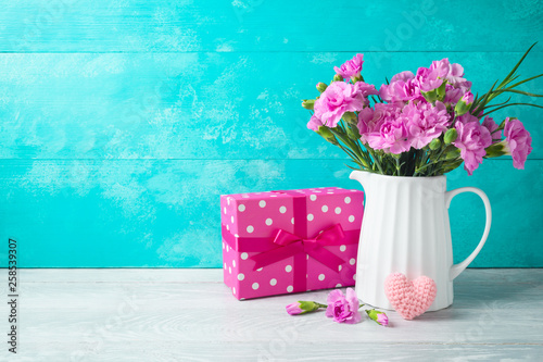 Mother's day background with flowers, heart shape and gift box on wooden table