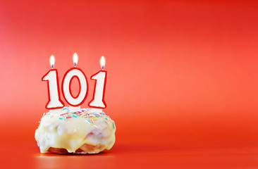 One hundred and one years birthday. Cupcake with white burning candle in the form of number 101....