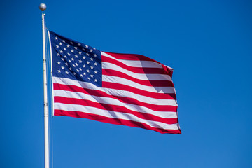Close up view of American flag flying against a clear blue sky