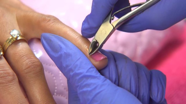 Beauty Treatment. Manicurist clipping hangnail from a baby finger with cuticle nippers - closeup