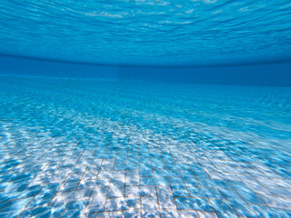 Transparent clear water in the pool. Underwater photo of the regulatory pool. Blue water pool bottom background. Summer theme.