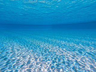 Transparent clear water in the pool. Underwater photo of the regulatory pool. Blue water pool bottom background. Summer theme.