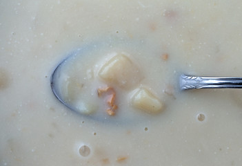 Top view of warm canned clam chowder with a spoon in the food