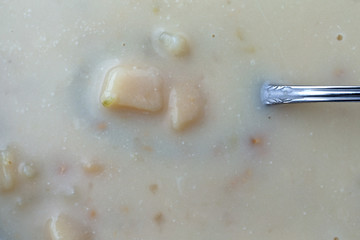 Close view of warm canned clam chowder with a spoon in the food