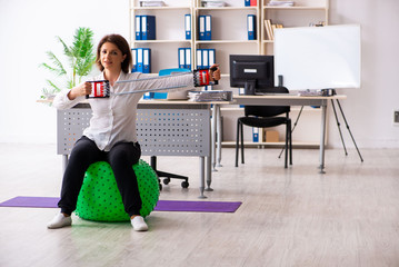 Middle-aged female employee doing exercises in the office 