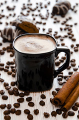 A cup of coffee with cinnamon and whipped cream. Coffee grains and chocolate gingerbread.