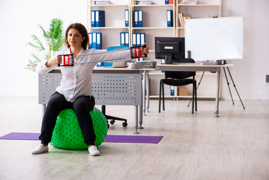 Middle-aged female employee doing exercises in the office