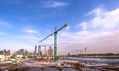 Fototapeta na wymiar construction site with Large Crane modern building foundation in dubai Business bay, construction site on Sunset background modern architecture 