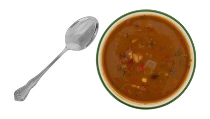 Top view of a bowl of chicken tortilla soup with a spoon to the side isolated on a white background.