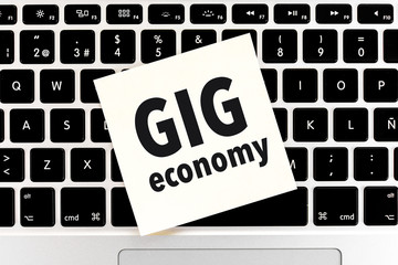 Concept of GIG ECONOMY with a close up adhesive note on keyboard notebook, laptop.