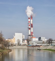 Obraz premium A river with a man in a kayak. Two industrial chimneys with a smoke