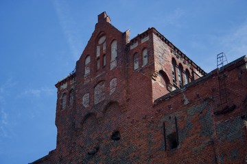 Old, ruined made of red brick wall below the roof