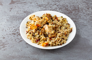 Chicken with pecans and wild rice on a plate on a gray background