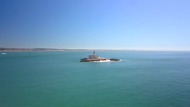 Aerial, drone shot, towards Bugio lighthouse, on the atlantic ocean, on a sunny day, near Oeiras coast and Tejo river, in Lisbon, Portugal