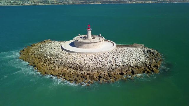 Aerial, orbit, drone shot, around Bugio lighthouse, on a rocky island, in the middle of the atlantic ocean, on a sunny day, near Oeiras coast and Tejo river, in Lisbon, Portugal