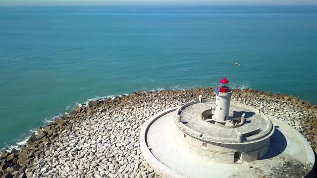 Aerial, drone shot, over Bugio lighthouse, on a rocky island, tilting up towards the atlantic ocean, on a sunny day, near Oeiras coast and Tejo river, in Lisbon, Portugal
