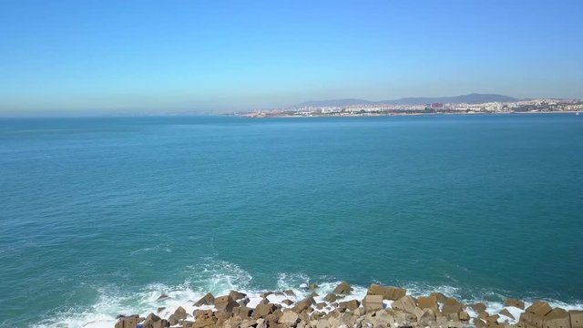 Flyover of Bugio lighthouse, on a rocky island, at the atlantic ocean, on a sunny day, a drone aerial shot near the Oeiras coast and Tejo river, in Lisbon, Portugal