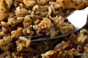 Close view of chicken with pecans and wild rice with a fork in the food
