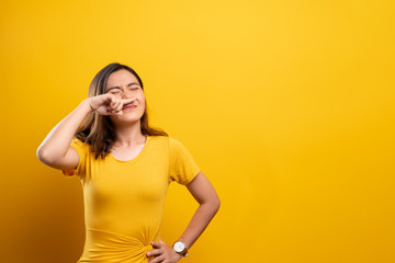 Woman sneezing isolated over yellow background