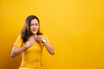 Woman has sore throat isolated over yellow background