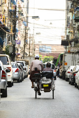 A unidentified Sai Kaa driver is carrying a passenger on his side car among the narrow streets of Yangon, Myanmar. The Sai Kaa rickshaw is a type of tricycle used in southeast Asia.