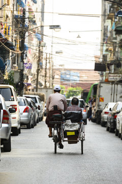 A unidentified Sai Kaa driver is carrying a passenger on his side car among the narrow streets of Yangon, Myanmar. The Sai Kaa rickshaw is a type of tricycle used in southeast Asia.