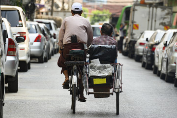 A unidentified Sai Kaa driver is carrying a passenger on his side car among the narrow streets of Yangon, Myanmar. The Sai Kaa rickshaw is a type of tricycle used in southeast Asia.