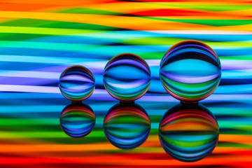 A row of three crystal balls with multicolored light painting behind them