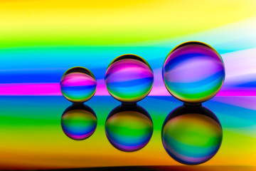 A row of three crystal balls with multicolored light painting behind them