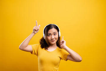 Woman with headphones listening music on isolated yellow background